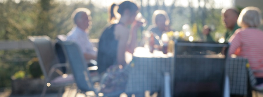 Verschiedene Generationen sitzen gemeinsam im Garten am Tisch